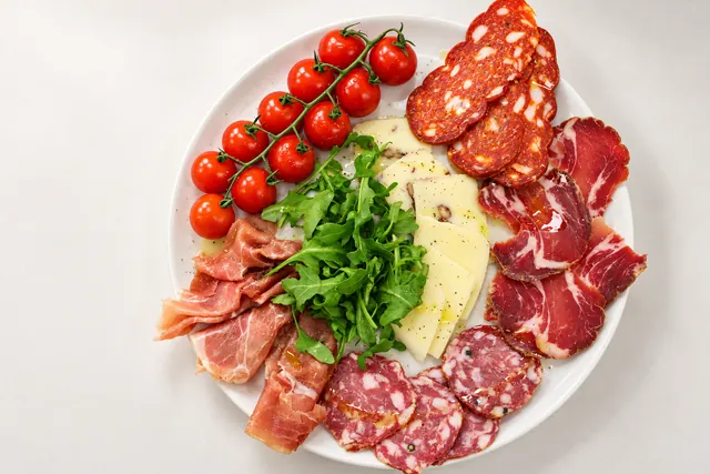 Antipasti-Platte mit Salami, Coppa, Prosciutto, Käse, Rucola und Kirschtomaten