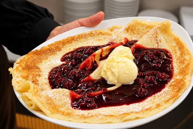 Crêpe mit heißen Kirschen, Vanilleeis und Puderzucker